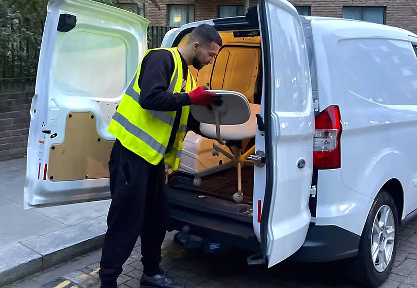 Driver loading large furniture items into the van